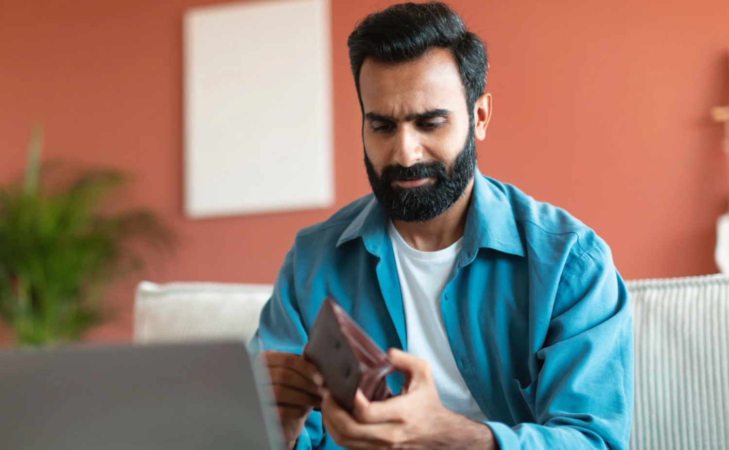 Man looking disappointed while looking in is wallet.